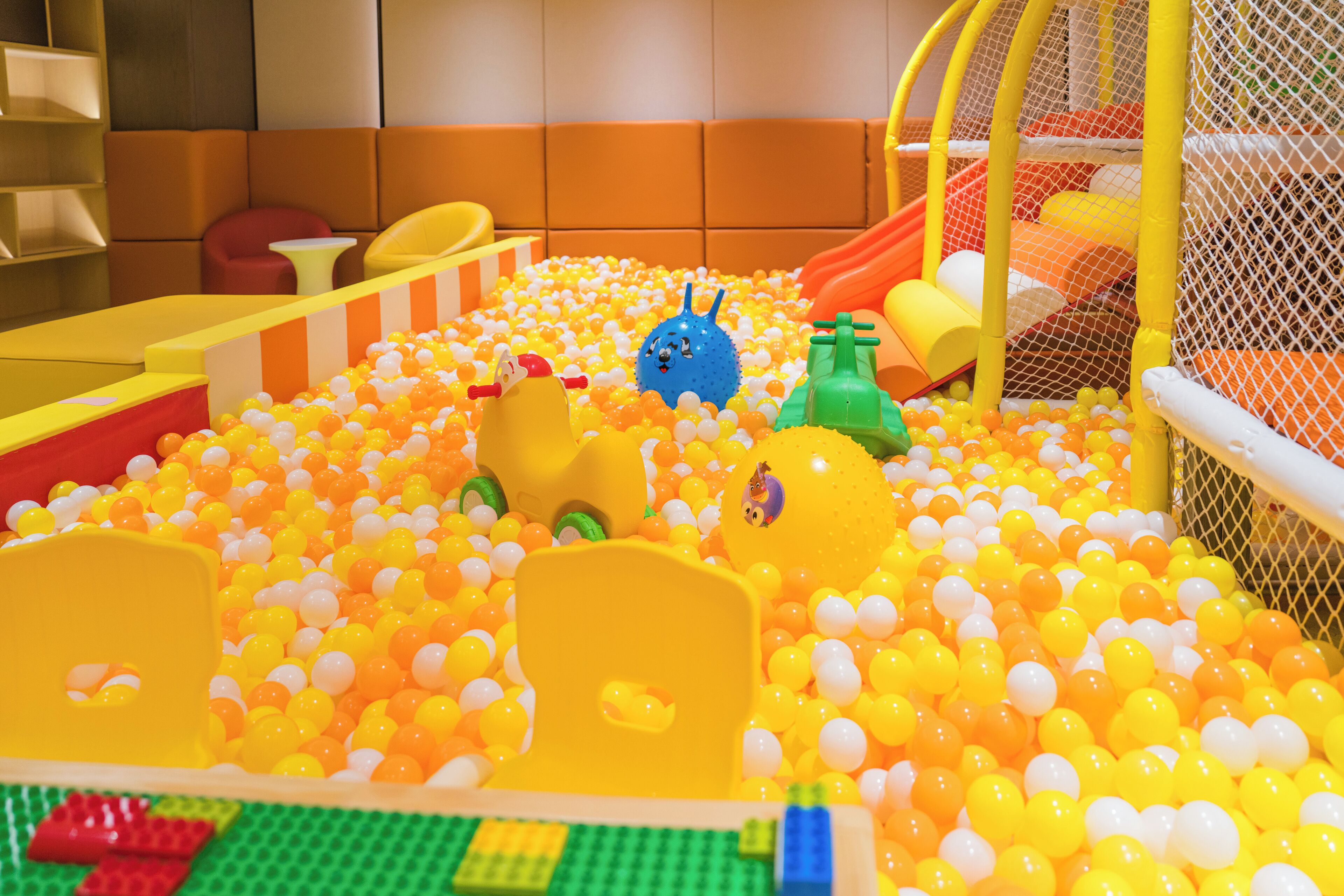 Un espace de jeux avec une piscine à balles, des toboggans et du mobilier souple.