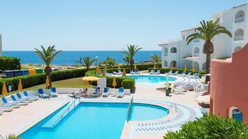 Una piscina al aire libre, sombrillas, tumbonas