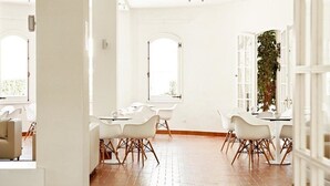 Um quarto amplo e bem iluminado, com paredes brancas, janelas grandes e piso de madeira.