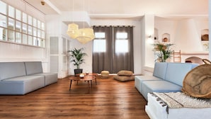 Uma sala de estar moderna com sofá seccional, mesa de centro redonda e uma grande janela com cortinas.