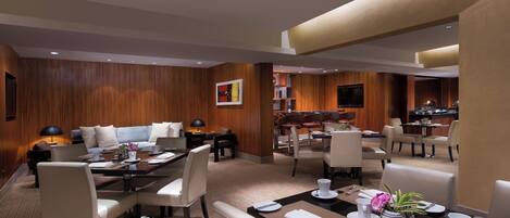 Un comedor de hotel moderno con paneles de madera, varias mesas y asientos cómodos.