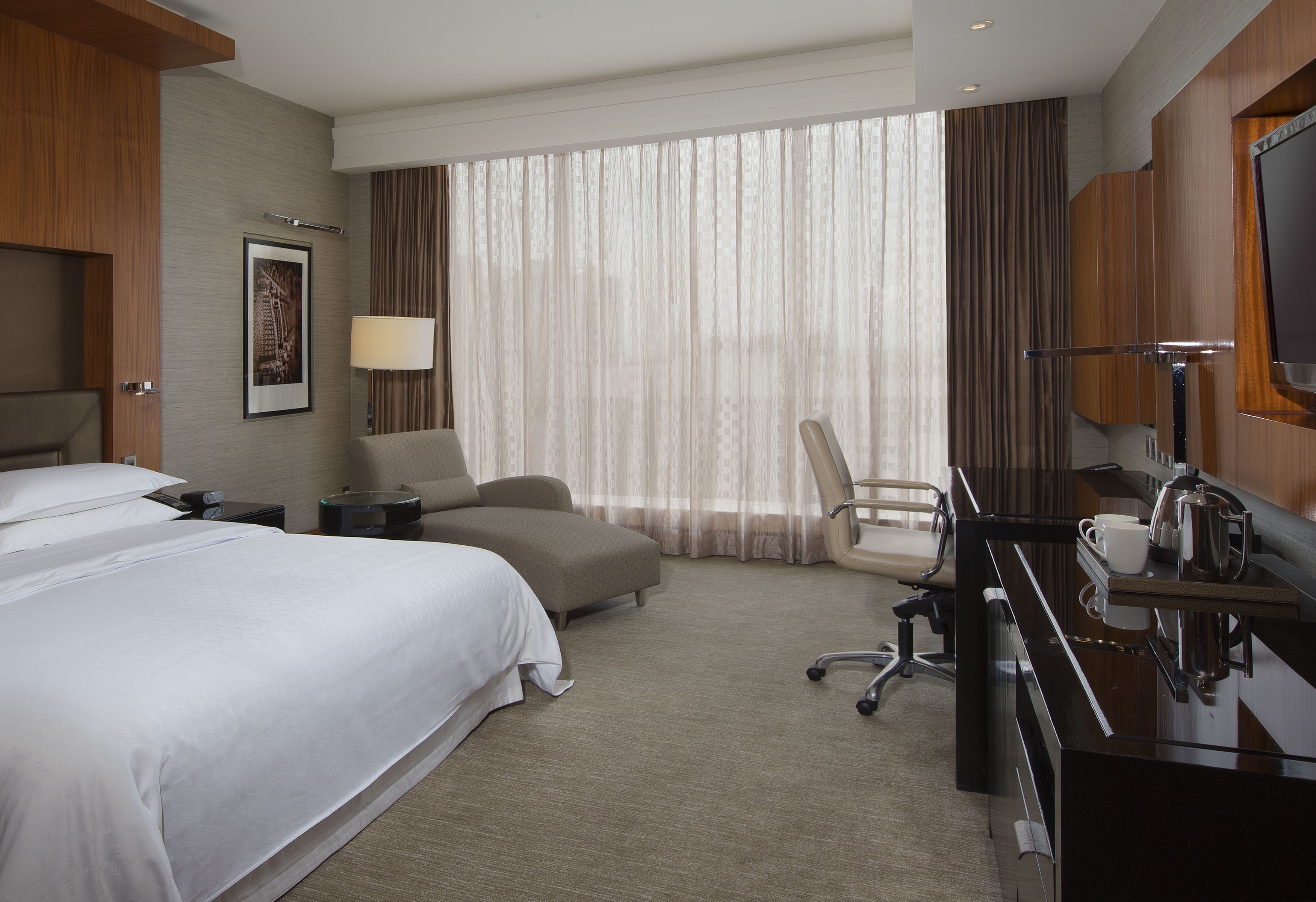 Une chambre d’hôtel avec un grand lit, un canapé, un bureau avec une machine à café et une télévision.