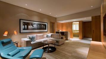 A modern living room with a sofa, a blue chair, a round table, and a framed picture on the wall.
