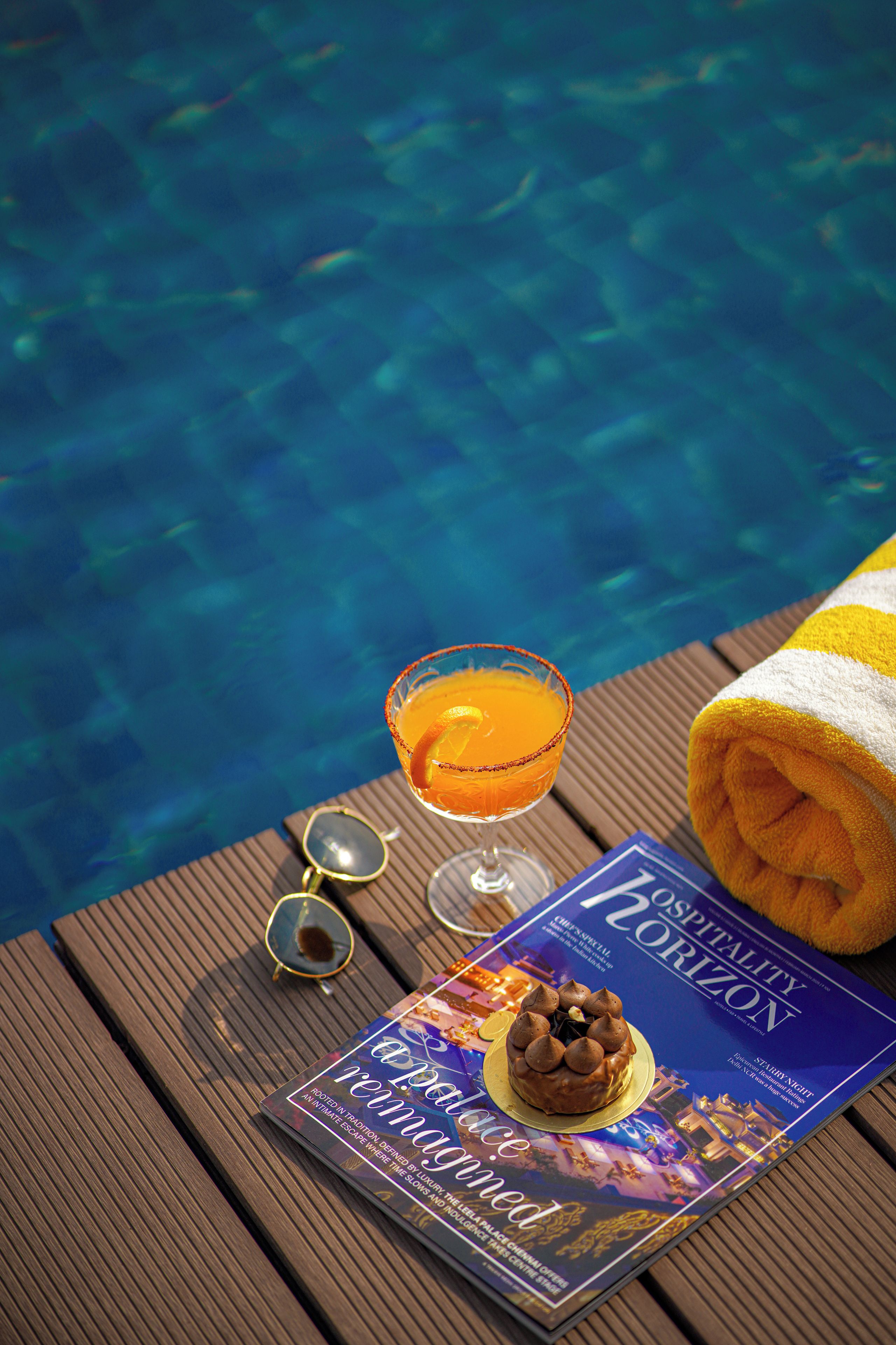 A magazine titled 'Hospitality Horizon' on a wooden surface near a pool.