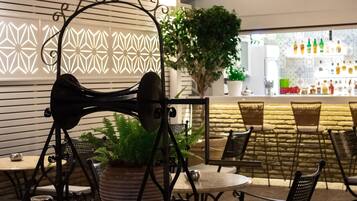 A bar area with a decorative black metal structure, wicker chairs, and a potted plant.