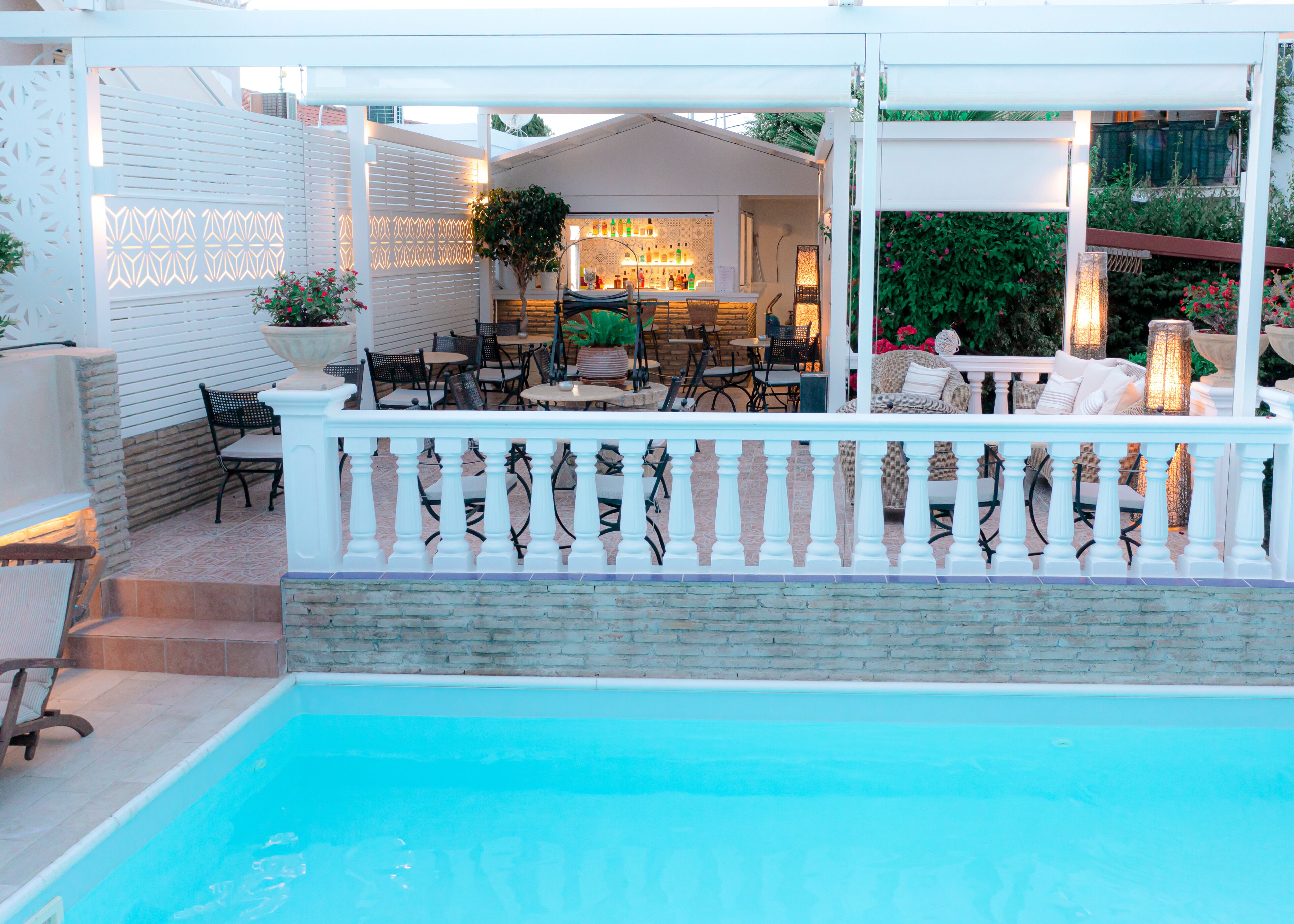 Un espace aménagé au bord de la piscine, comprenant un coin salon couvert, un bar et une piscine.
