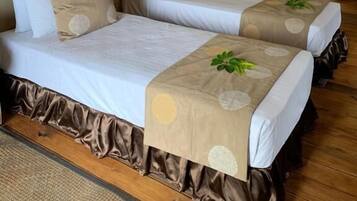 A tented accommodation with two beds, each with a pillow and a bedside lamp.