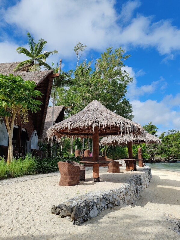 A beachside resort with thatched-roof structures, wicker furniture, and a sandy beach. - Ratua Private Island Resort (Ratua Island)