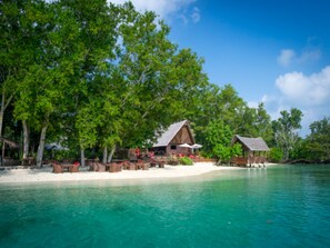 Een strandresort met houten hutten, een zandstrand en helder turquoise water.