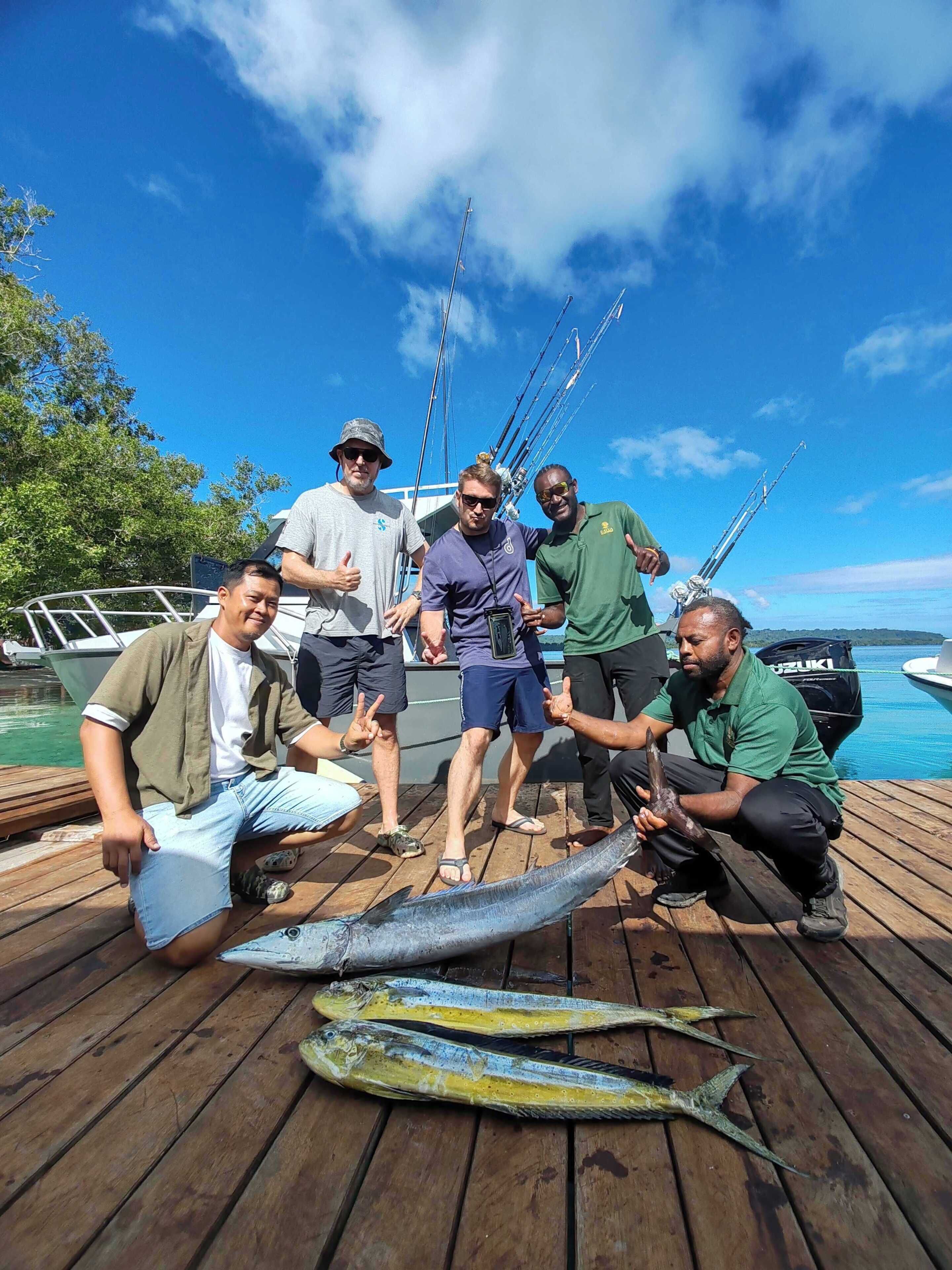 Un groupe de personnes se tient sur une jetée en bois et tient un gros poisson.