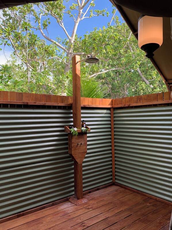 A wooden deck with a metal railing, a wooden planter with plants, and a ceiling light fixture.
