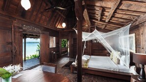 Una habitación de madera con una cama, una mesa y vista al mar.