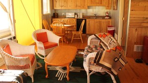 Una cocina compacta con armarios de madera y una zona de comedor con mobiliario de mimbre.