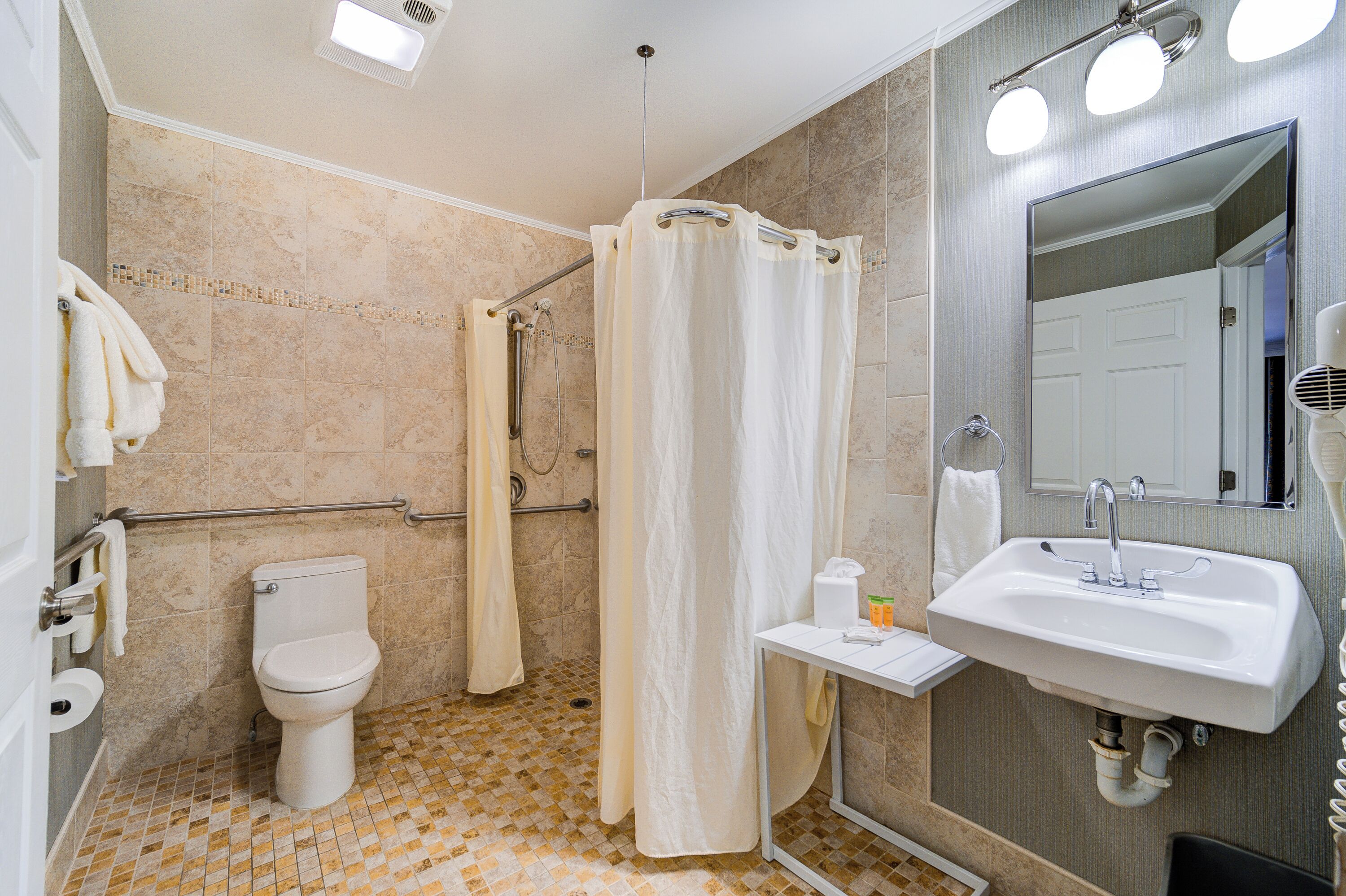 Un baño con inodoro, ducha, lavabo y espejo.