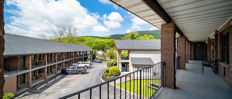 Un motel con estacionamiento techado, un pequeño jardín y vistas a un paisaje montañoso.