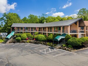 A motel with a two-story structure, a parking lot, and a small water feature.