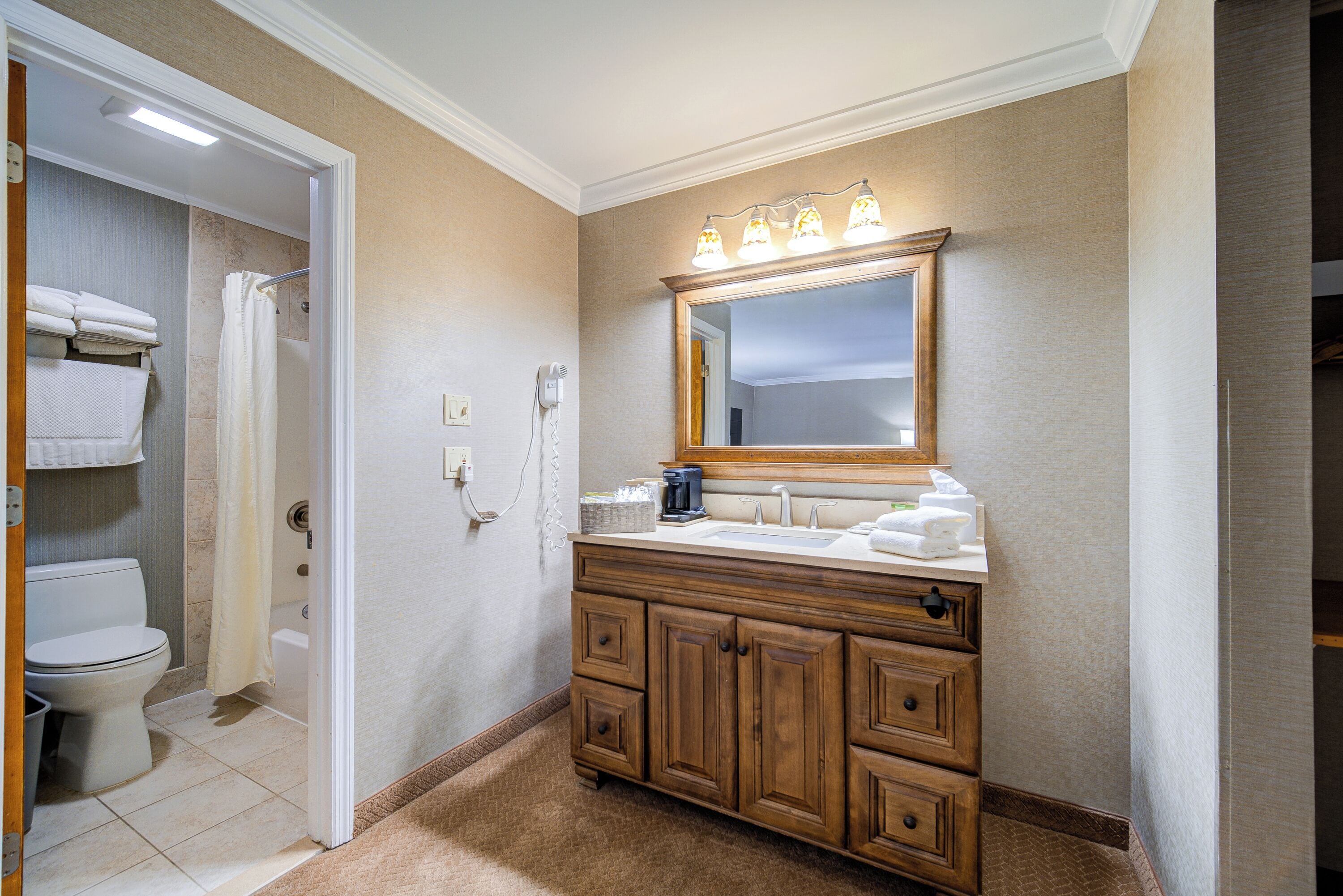 A bathroom with a wooden vanity, a large mirror, and a shower area.