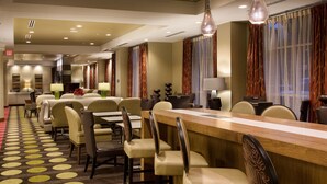 Una hall d'albergo con una lunga reception, diverse zone salotto e un tappeto decorato.