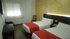 Een hotelkamer met twee bedden, een bureau, een stoel en een telefoon.