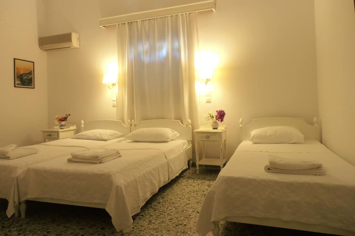 Une chambre d’hôtel avec deux lits, chacun étant équipé d’un oreiller et d’une serviette pliée. On y trouve des tables de chevet avec des lampes et un petit vase avec des fleurs.