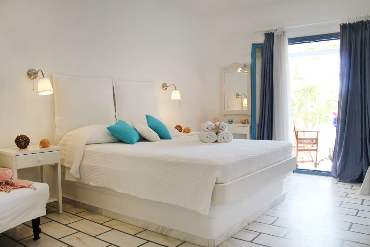 Une chambre avec un grand lit, deux tables de chevet, un miroir et une vue sur l’extérieur.