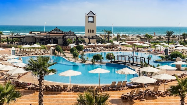 Un resort con una piscina grande, tumbonas, sombrillas y una torre.
