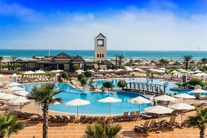 Un resort con una piscina grande, tumbonas, sombrillas y una torre.