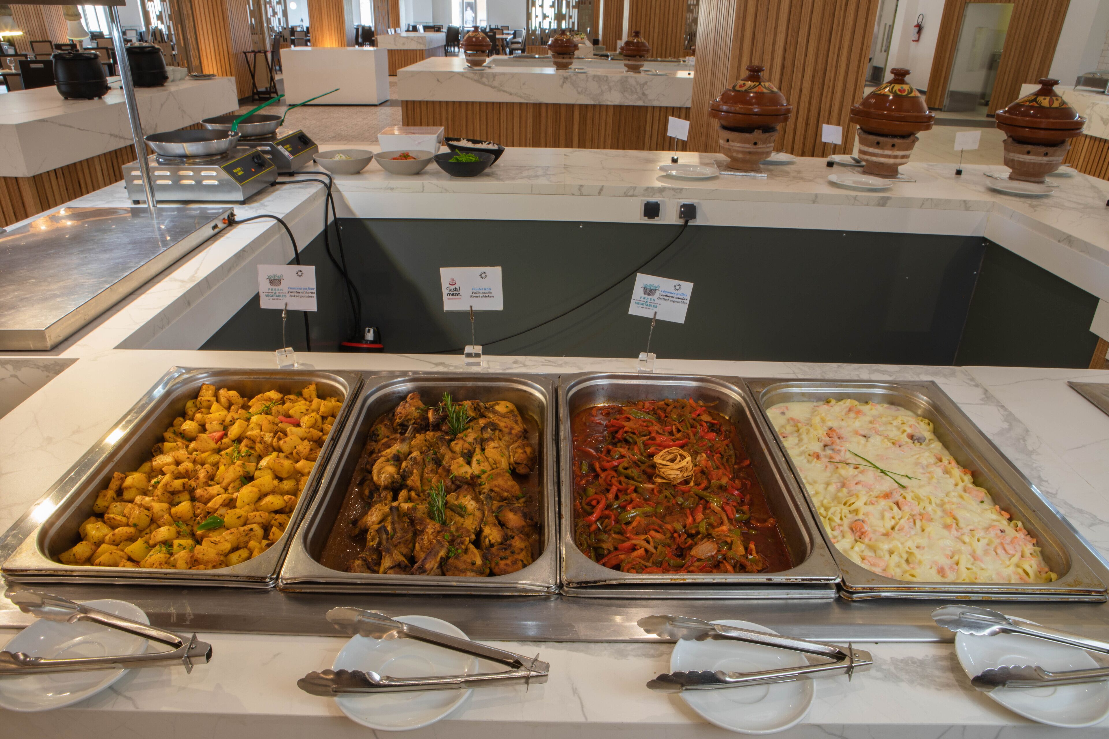 Un bufé con diversas opciones de comida, incluyendo una sección con varios tipos de carne y un plato de pasta.