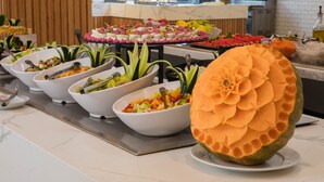 Un bufé con diversos platos y una elaborada escultura de melón en el centro.