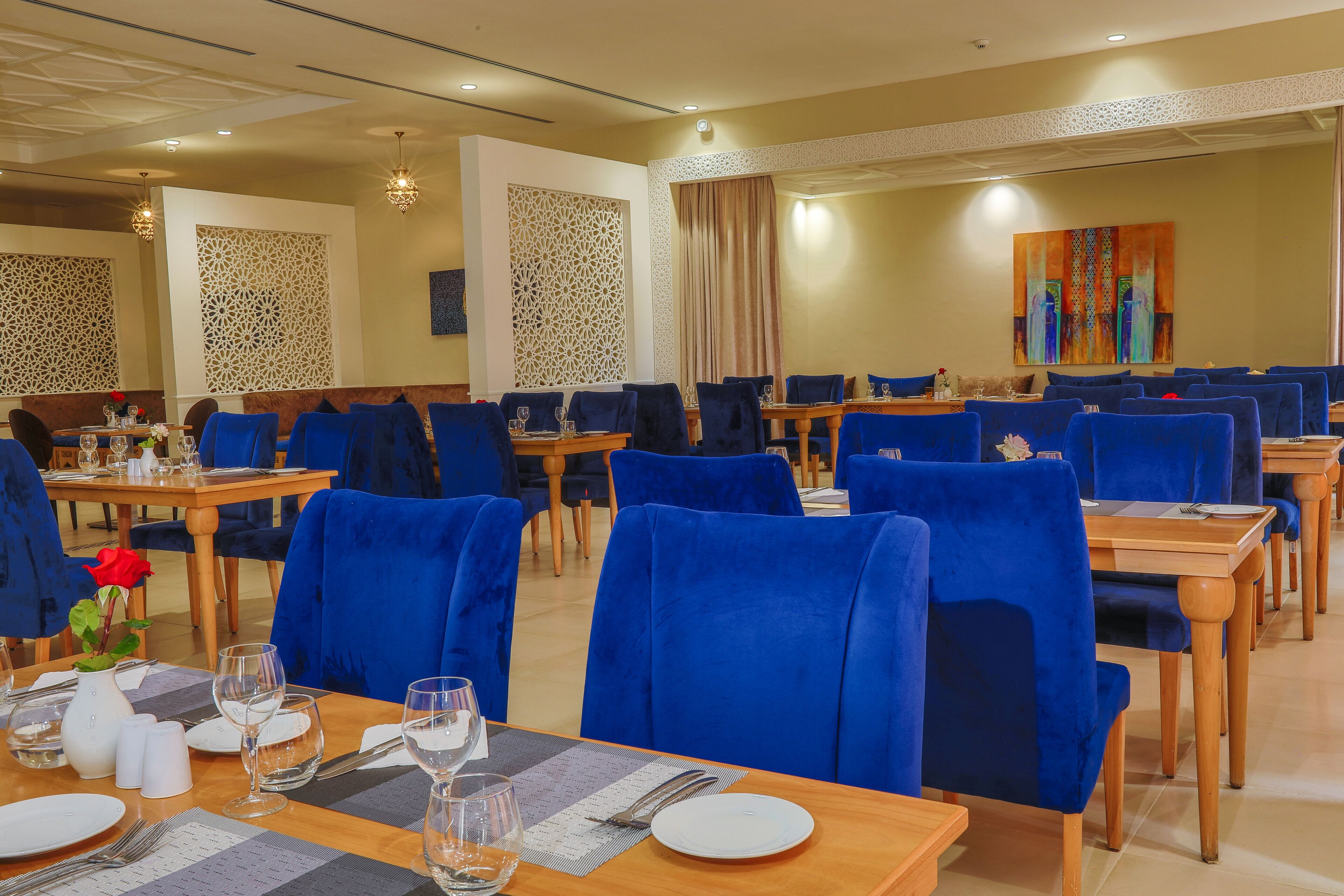 A restaurant with blue velvet chairs, wooden tables, and decorative wall panels.