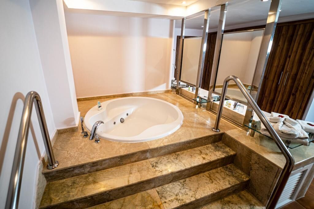 A modern bathroom with a freestanding bathtub, marble steps, and a glass shower enclosure.