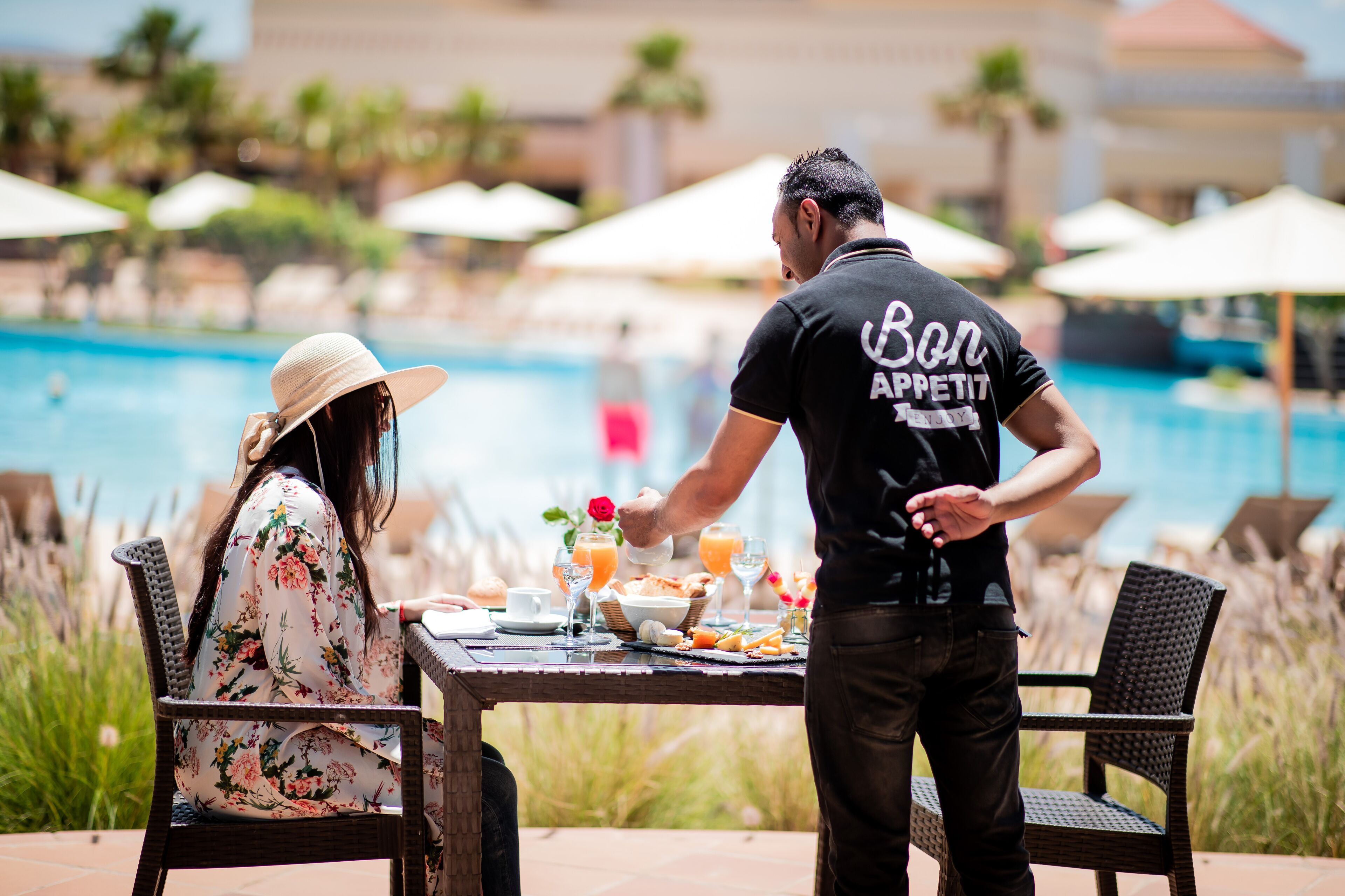 A dining table with breakfast items and a pool in the background.
