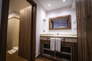 Un baño con tocador de madera, un espejo y zona de ducha.