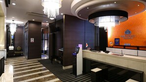 A hotel reception area with a check-in counter, a digital display, and a chandelier. - APA Hotel Ikebukuro Eki Kitaguchi (Tokyo)