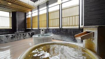Un onsen japonés tradicional con baños de piedra, un banco de madera y una pared de piedra con una ventana.