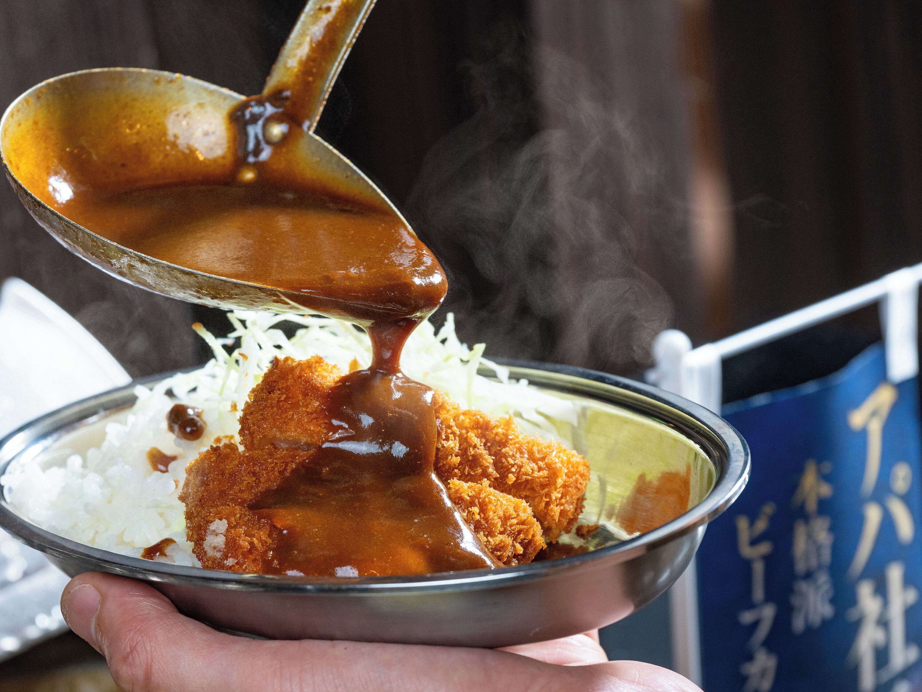 A bowl of food with a sauce being poured over it.