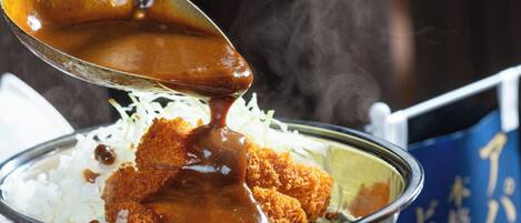 A bowl of food with a sauce being poured over it.