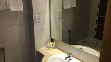 Un baño con lavabo, espejo y ducha.
