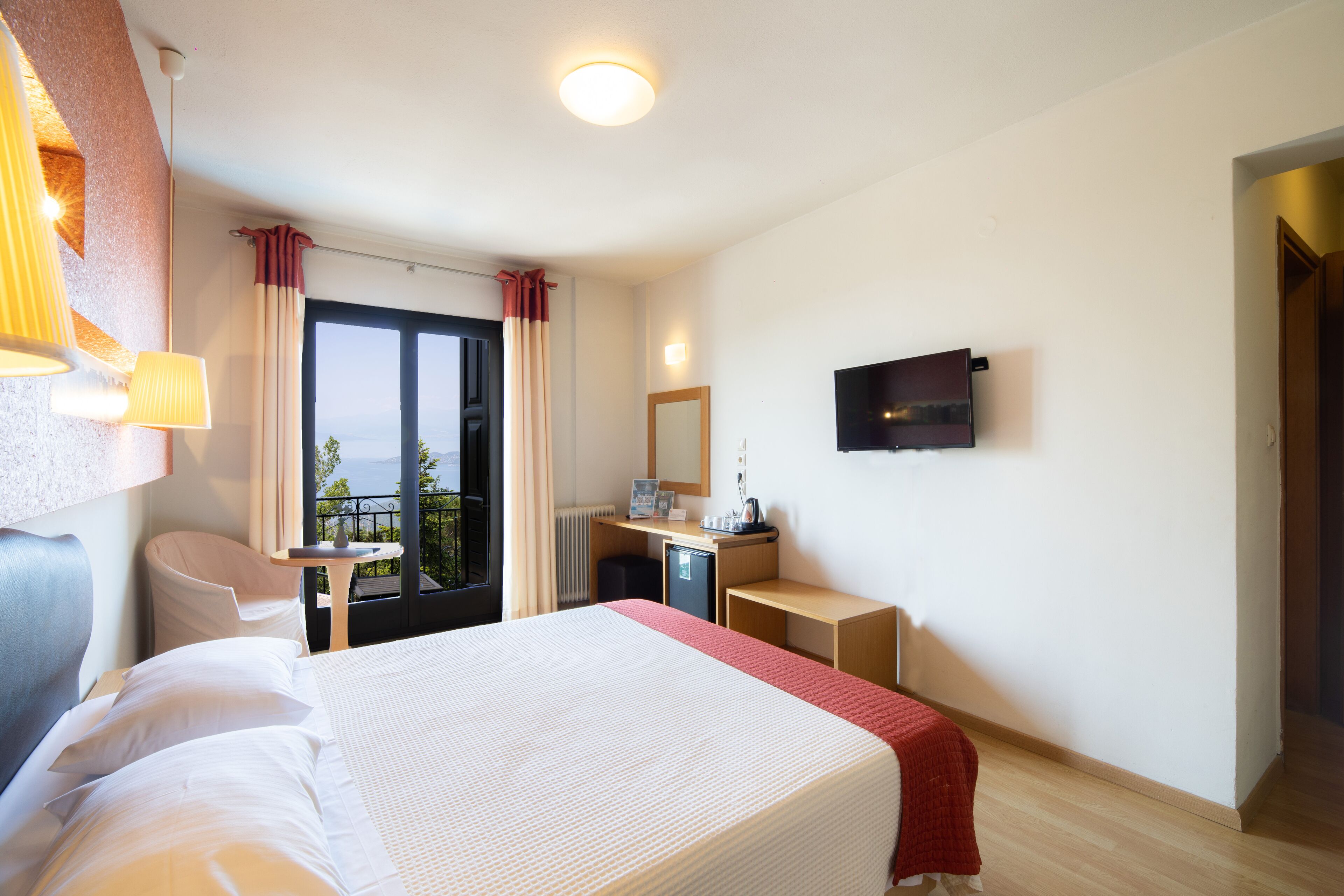 Habitación de hotel con cama, escritorio, silla y televisor montado en la pared.