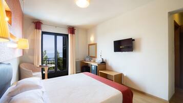 Habitación de hotel con cama, escritorio, silla y televisor montado en la pared.