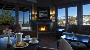 A cozy living room with a fireplace, seating area, and a view of the outdoors. - Portaria Hotel (Volos)