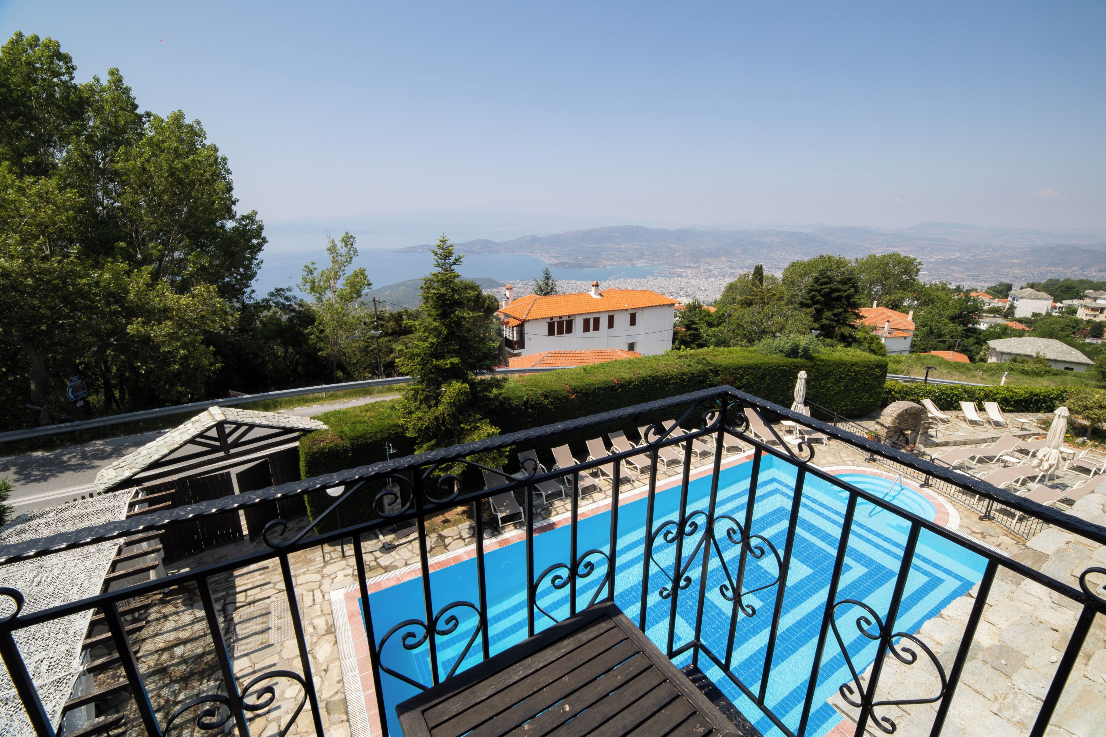 A pool with a blue and white pattern, surrounded by a black metal railing. In the background, there is a view of a cityscape with mountains and a clear sky.