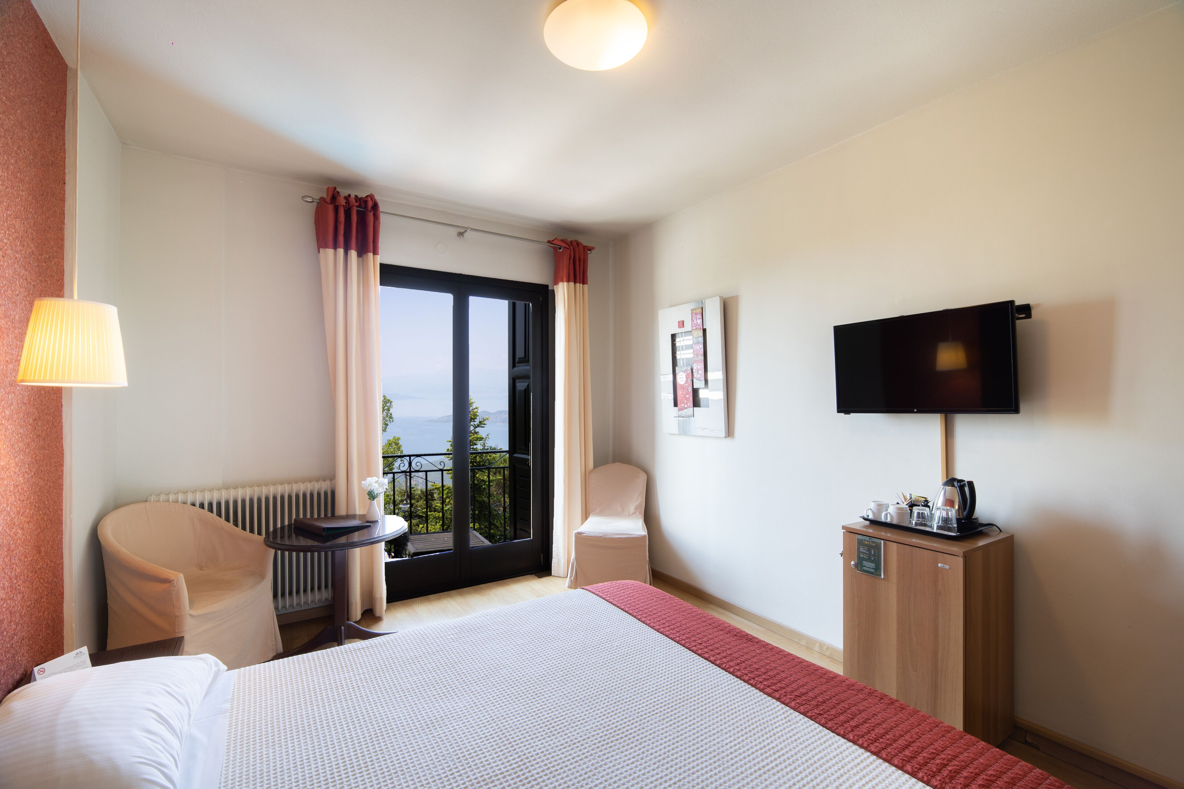 Una habitación de hotel con una cama, una silla, un escritorio, un televisor y vistas al exterior.