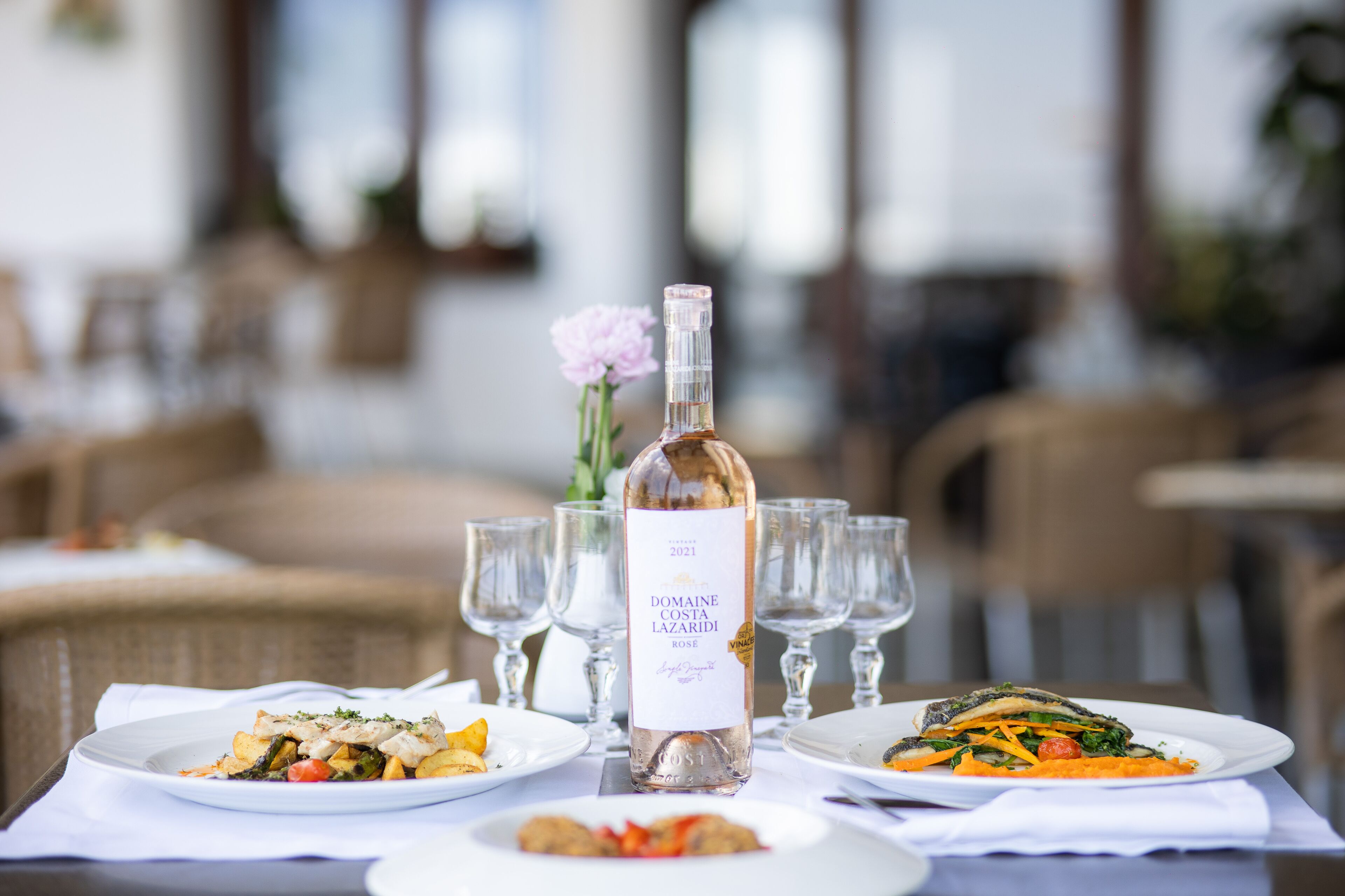 A dining table with plates of food, a bottle of wine, and wine glasses.