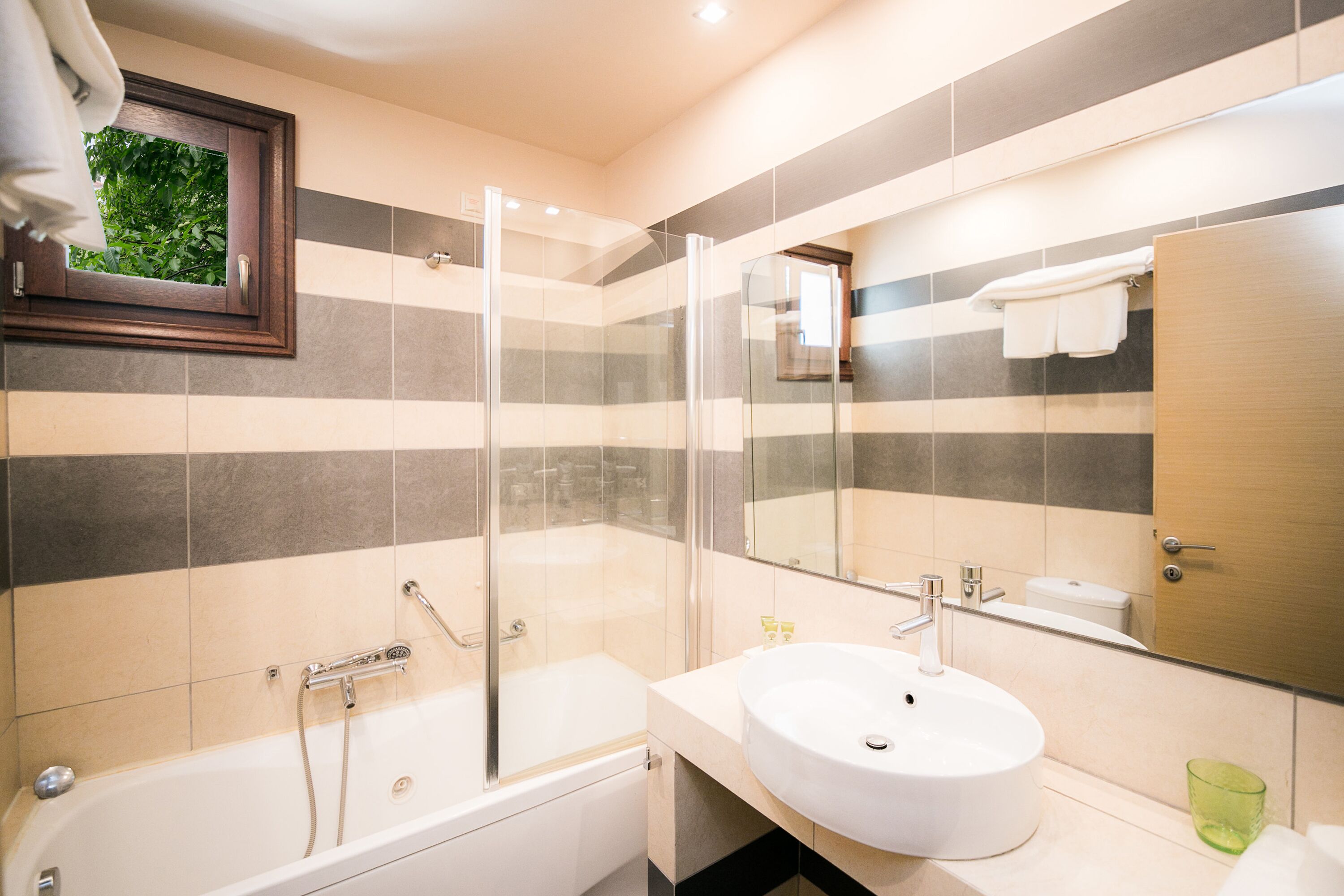A modern bathroom with a bathtub, a glass-enclosed shower, and a sink with a mirror above it.