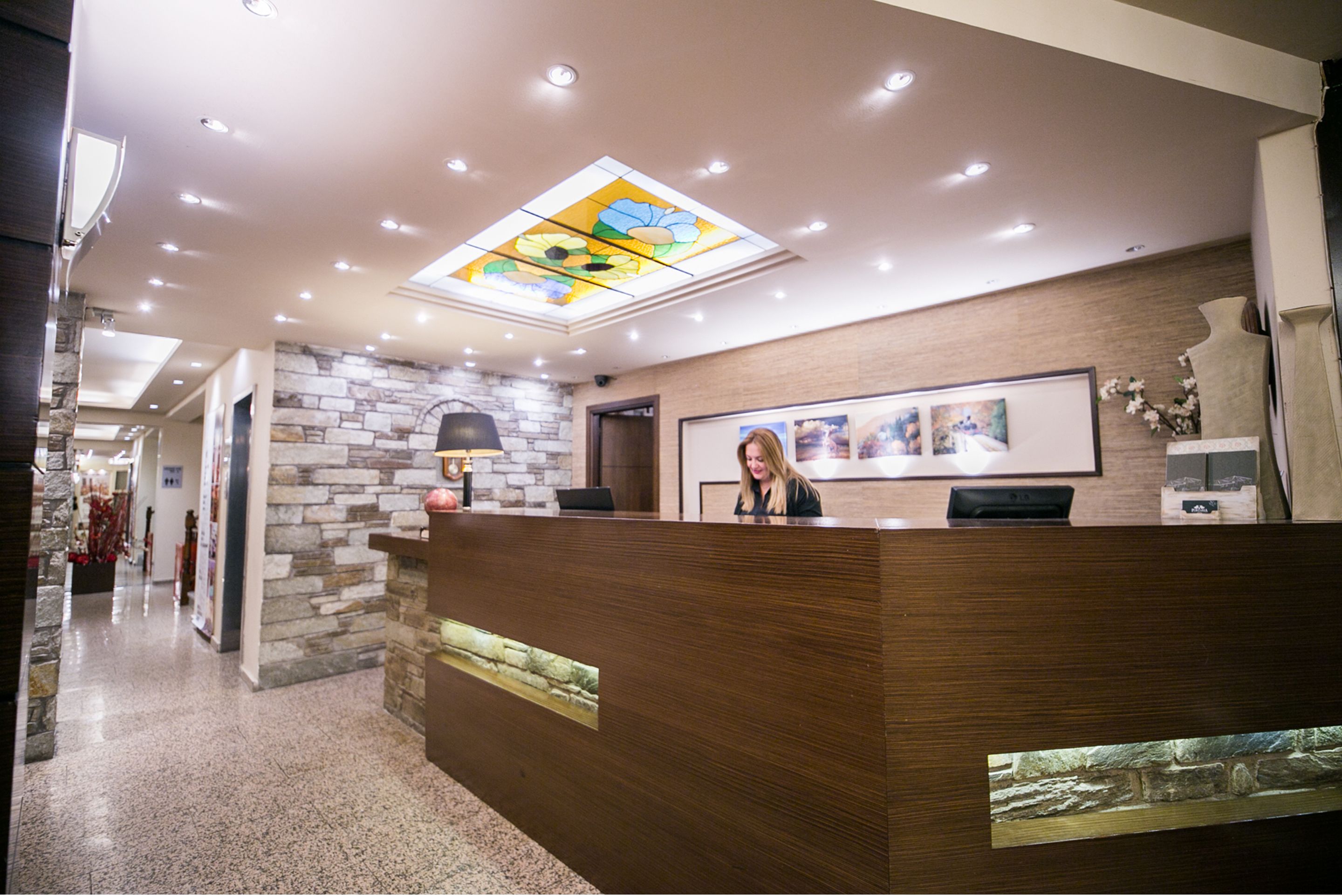 A reception area with a wooden reception desk, stone wall, and a skylight.