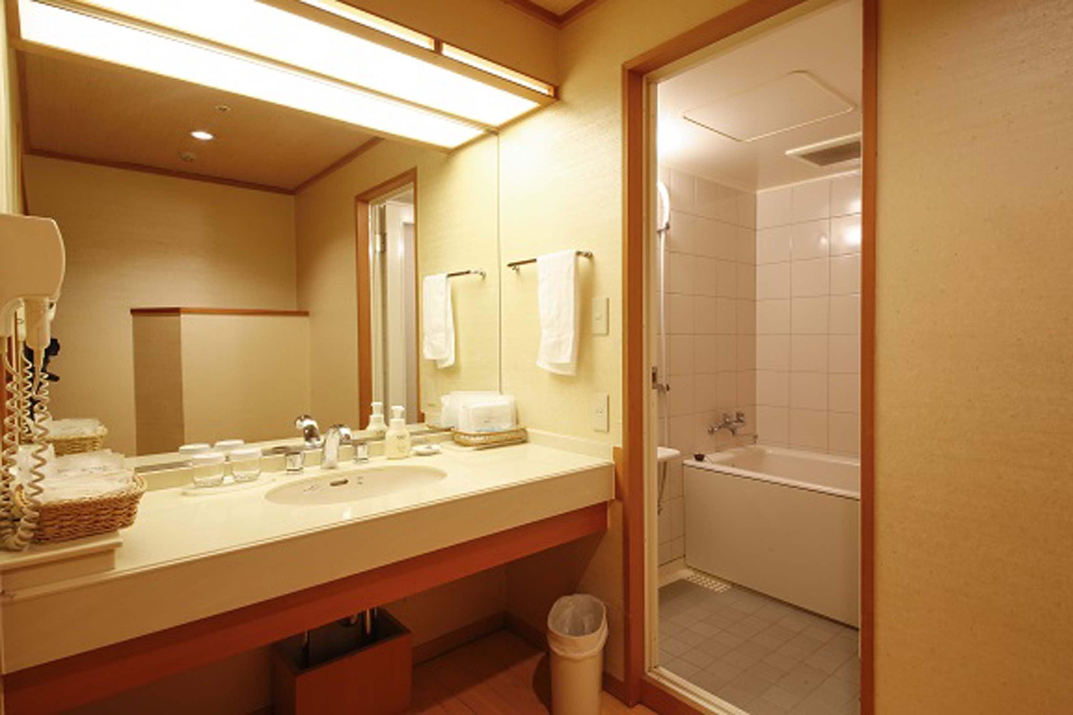 A bathroom with a double sink, a mirror, a towel rack, and a bathtub.