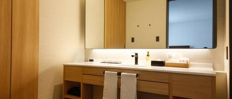Un baño moderno con tocador de madera, un espejo grande y toallas ordenadamente dobladas.