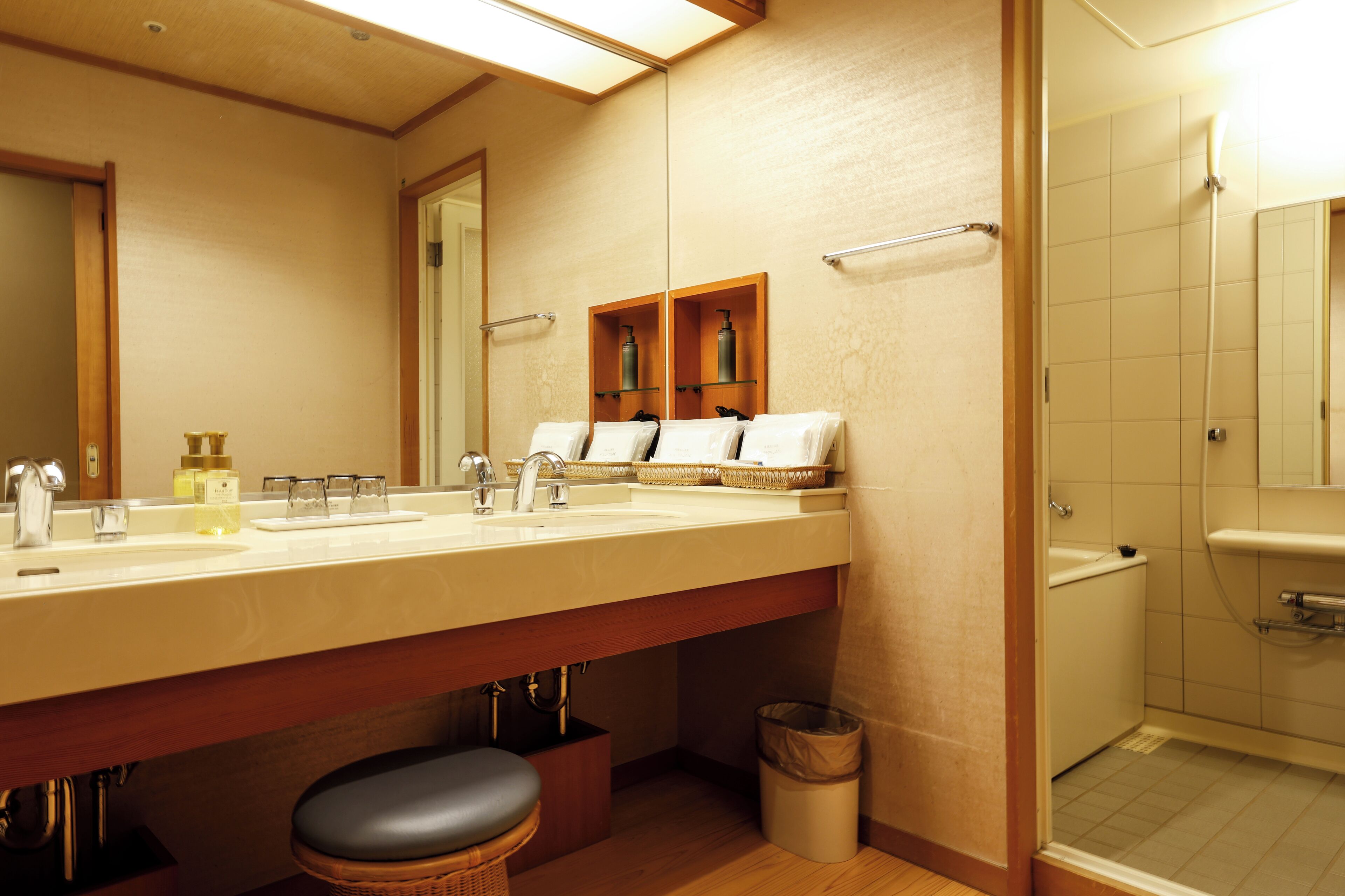 Une salle de bain moderne avec un grand lavabo, un miroir et des étagères en bois où sont rangés les produits de toilette.