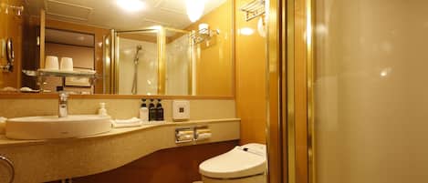 Un baño de hotel con lavamanos, espejo, inodoro y ducha.